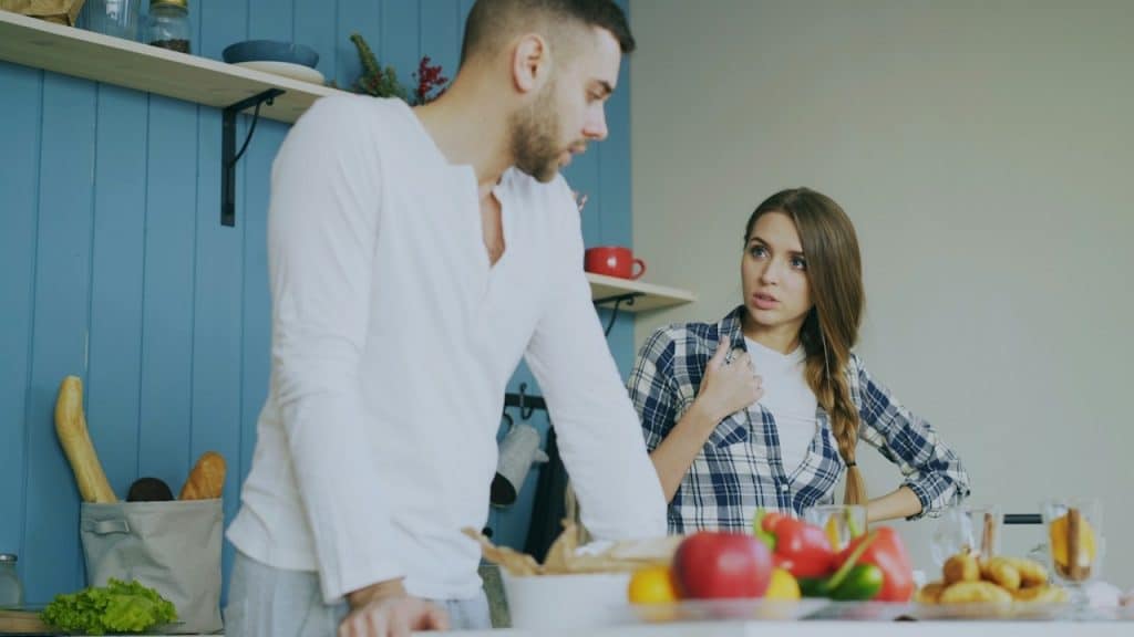 A man and a woman are standing in a kitchen, seemingly having a serious discussion or argument.