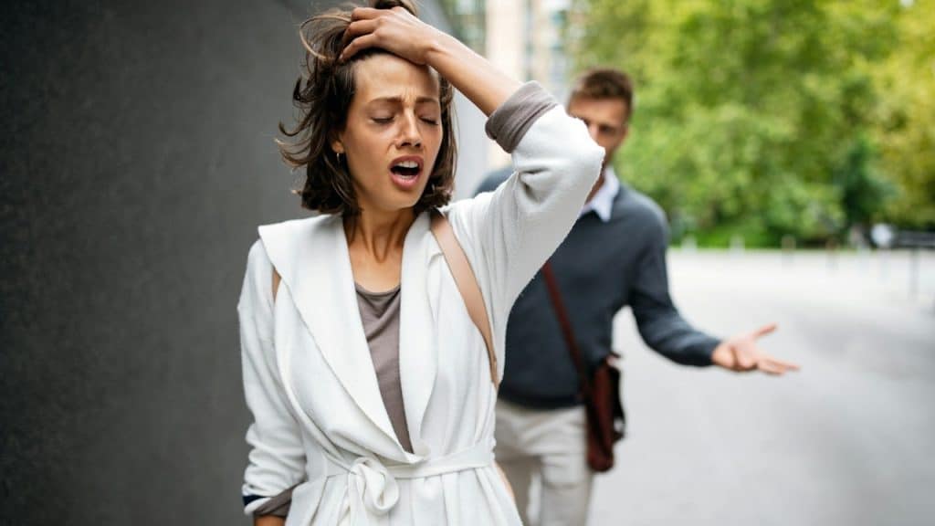 A woman walking away from a man while he tries to explain himself.