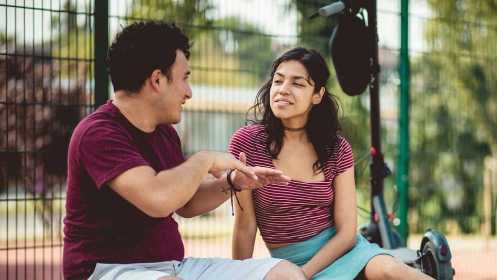 A couple sitting outdoors near an electric scooter.