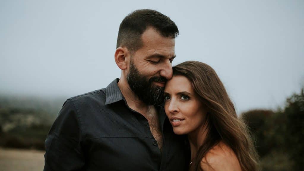 A man with a full beard embracing a woman with long hair.