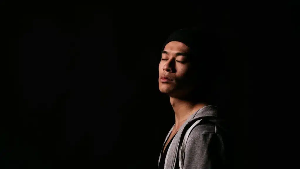 A young man standing with his eyes closed.