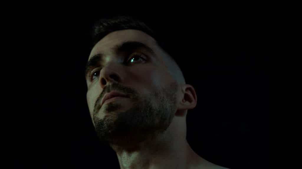 A lightly bearded man looking upwards with an intense expression.