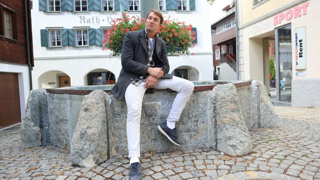 A man sitting on a stone bench in front of a building.
