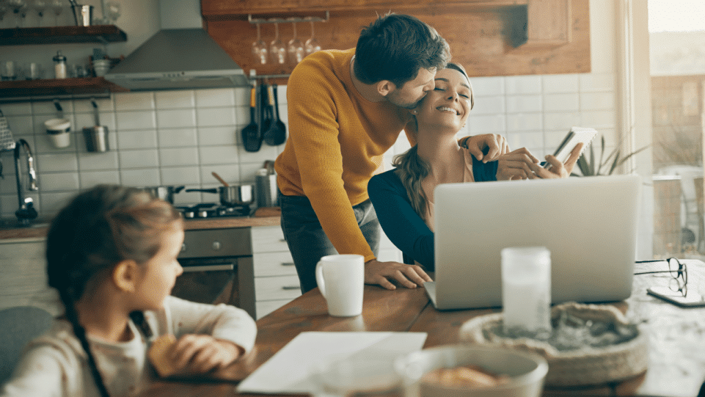 A man kissing his wife while she works