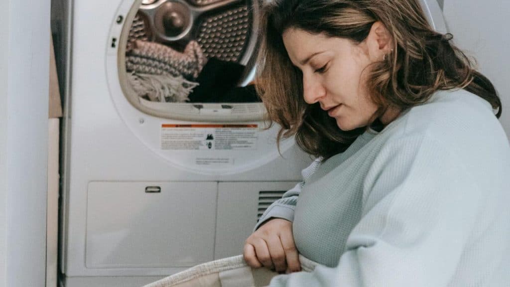 A woman loading clothes into a dryer in a laundry room.