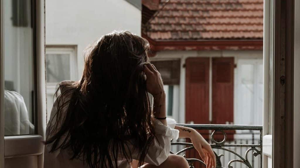 A person sitting by an open window and looking outside.