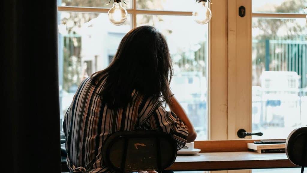 A person sitting at a café table looking out the window.