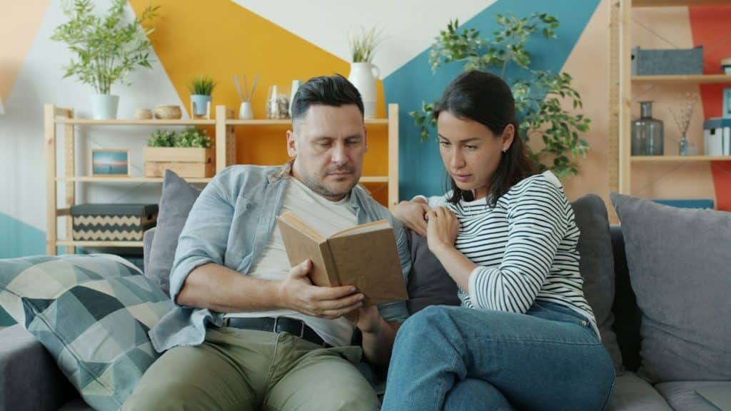 A man showing his favorite book to his wife.