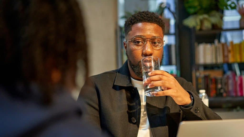 A man sitting at a table with a glass of water in front of him.