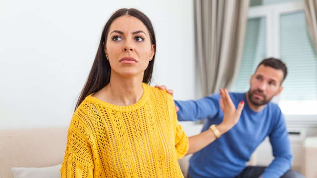 A stressed young man saying sorry after a quarrel to his frustrated wife.