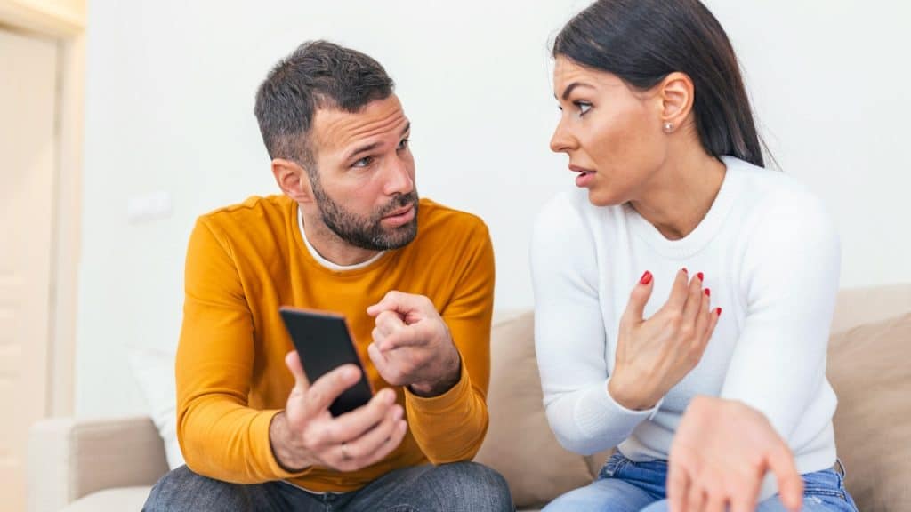 A man asking for an explanation from his cheating wife sitting with him.