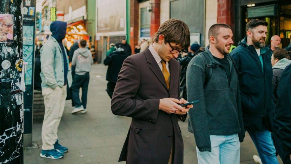 Three men passing a man standing on a city sidewalk.