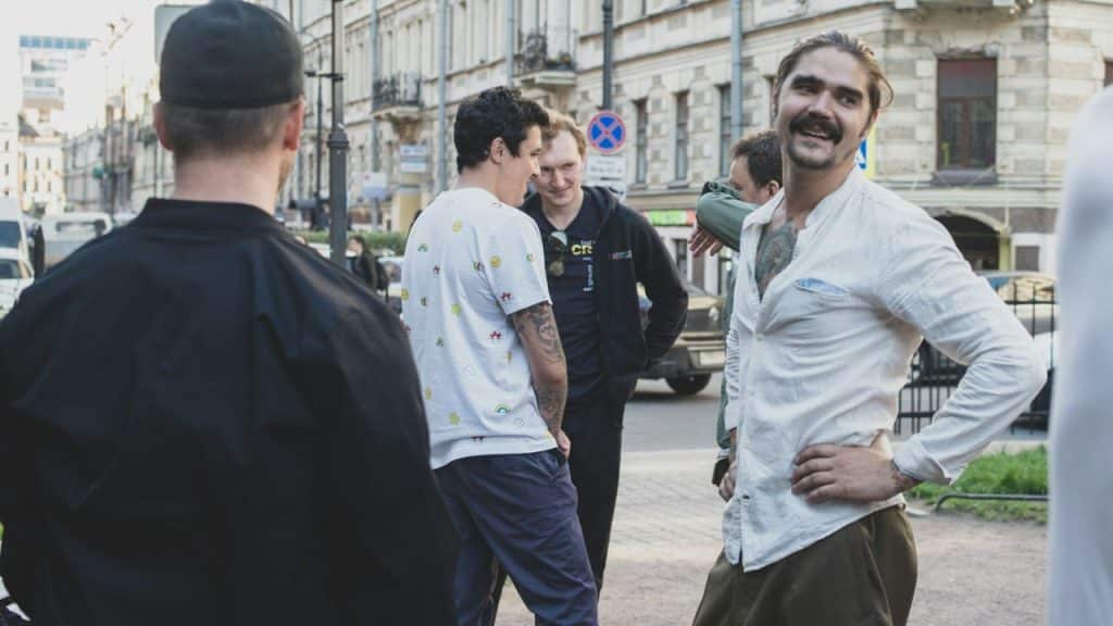 A group of four men talking and smiling on a city street corner.