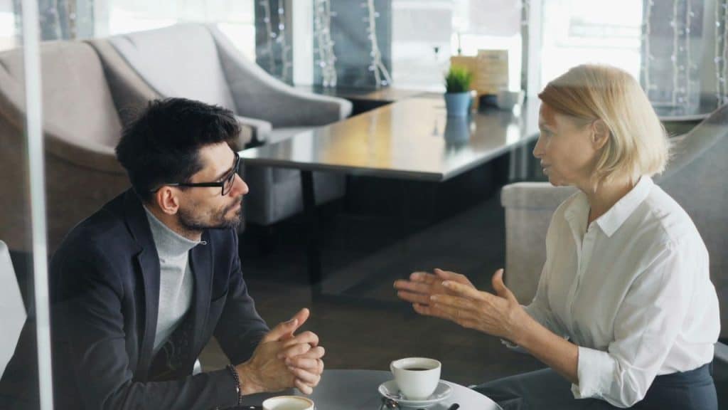 A couple sitting at a cafe table, having an intense conversation over coffee.