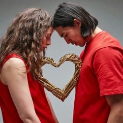 A man and woman close to each other and have a heart figure between them