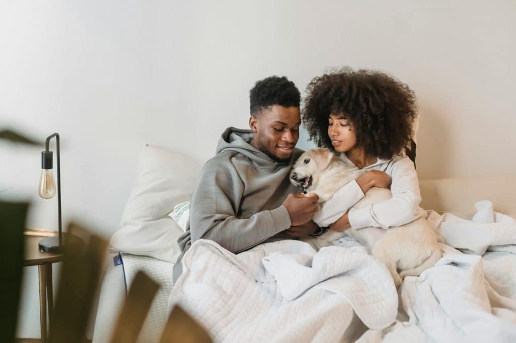 A man and woman at the bed with their dog 