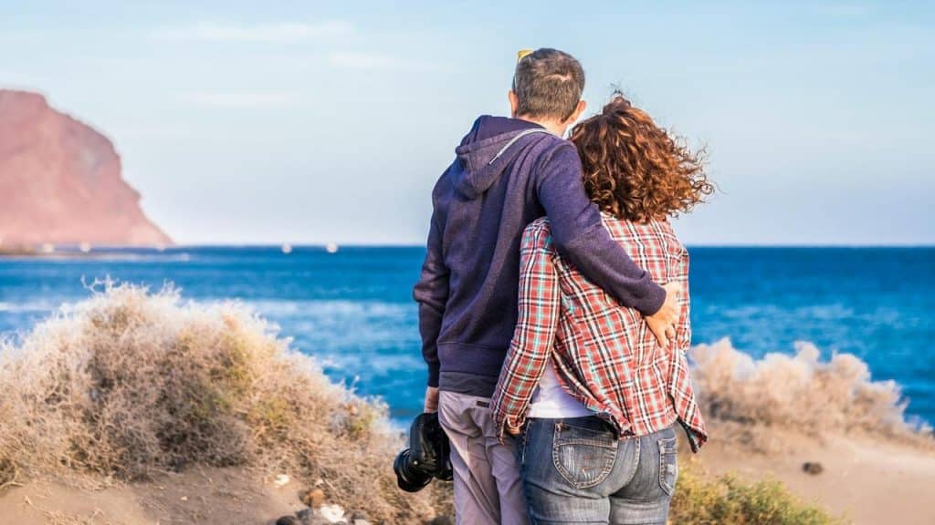 A couple standing together while admiring the beach view.