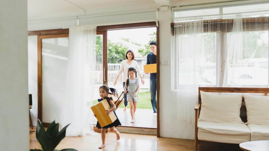 A family moving into a new home carrying moving boxes.