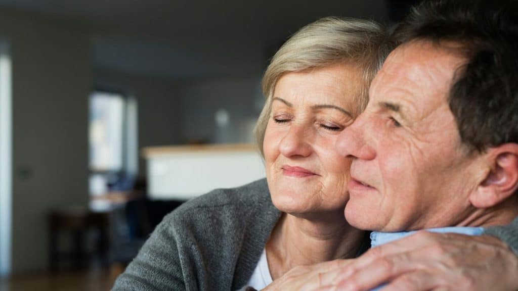 An older couple enjoying a quiet moment together while hugging each other.