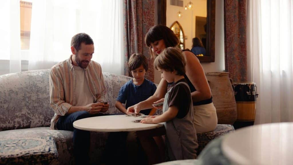 A family of four sitting around a table playing cards together in a cozy living room.