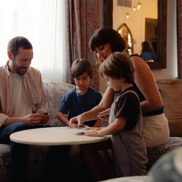 A family of four sitting around a table playing cards together in a cozy living room.