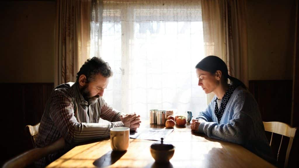A couple sitting at a table and looking down while not talking.