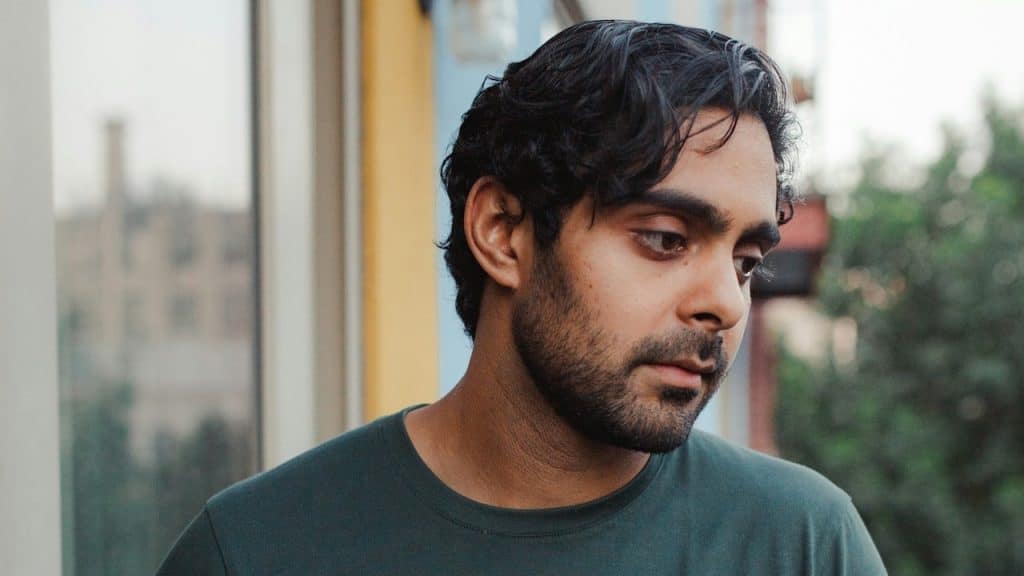 A lightly bearded man looking depressed.