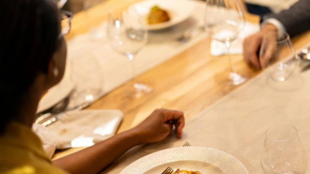 A restaurant scene with a plated meal, fine wine, and elegant table setting.