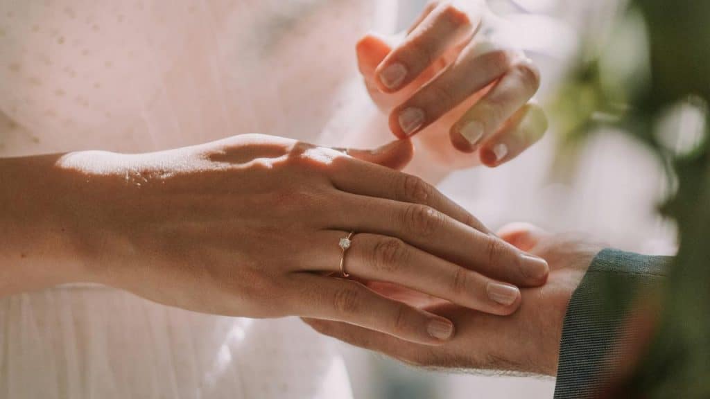 A close-up of a personโs hand showing off a sparkling engagement ring.