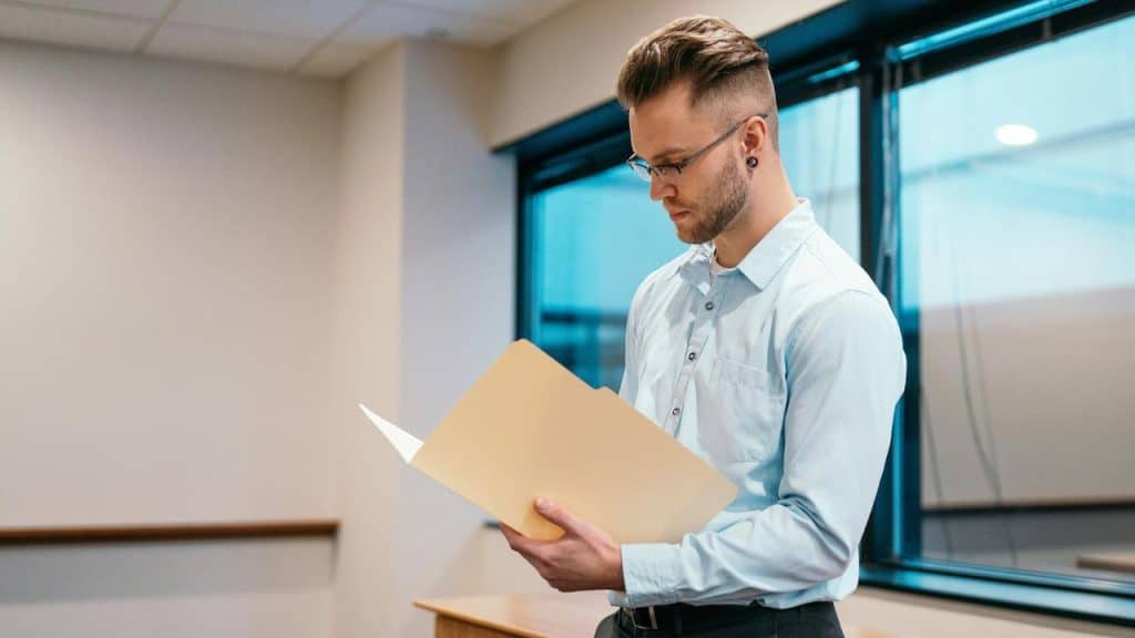 A man reviewing papers from a folder in a modern office setting.