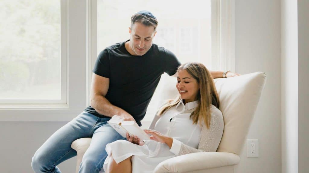 A man and woman reading a book by the window.