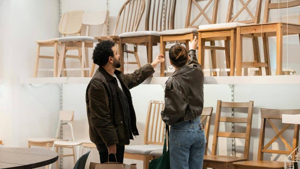 A couple browses wooden chairs on display at a furniture store.