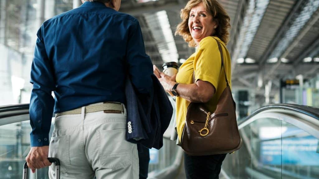 A woman smiling with coffee beside a man on an escalator.