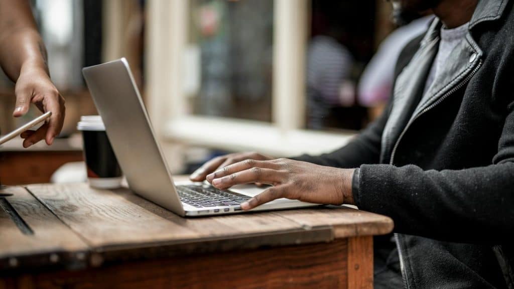 A person working on a laptop with coffee on the table.