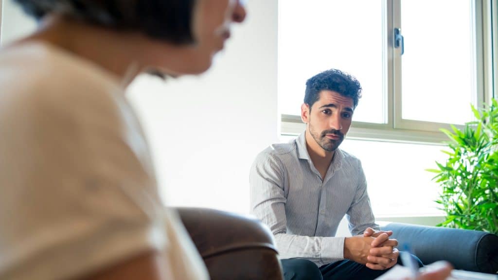 A man looking seriously at a person, who is blurred in the foreground.