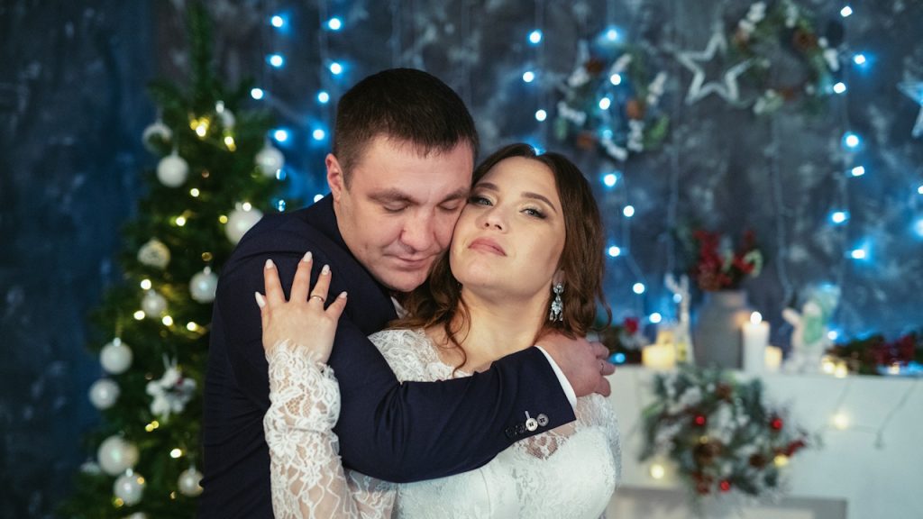 A man in a suit is embracing a woman in a white lace dress.
