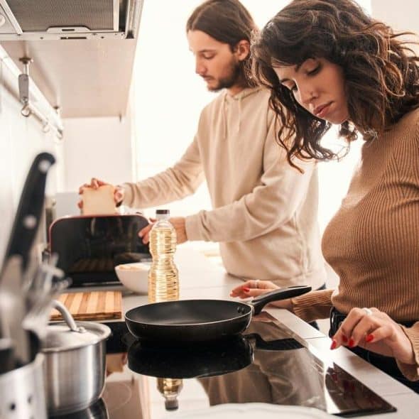 A couple cooking together in a kitchen.