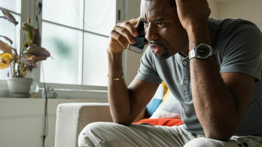 A worried man speaking on the phone in a quiet room.
