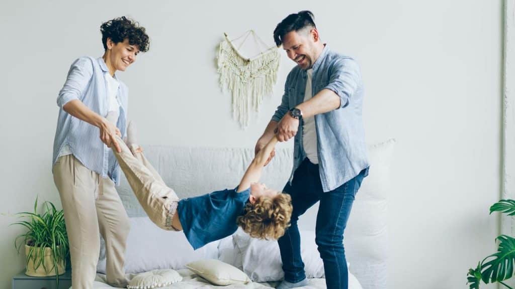 A couple playing with their child in a bright room.