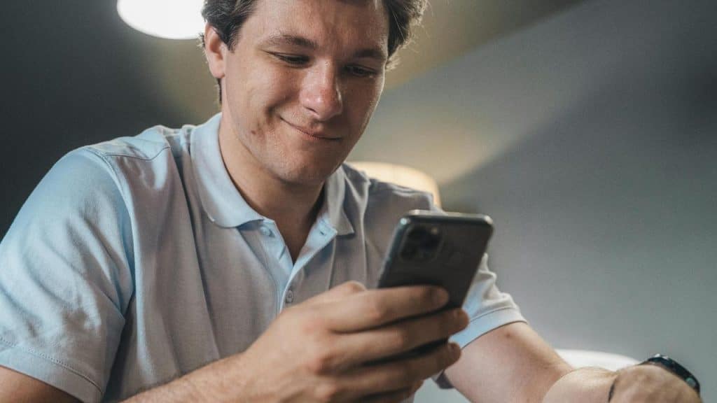 A man smiling while looking at his phone.
