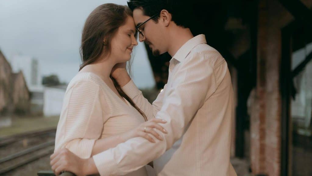 A couple standing close together with their foreheads touching lovingly.