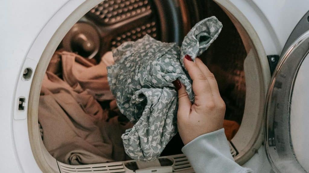 A person taking clothes out of a washing machine.