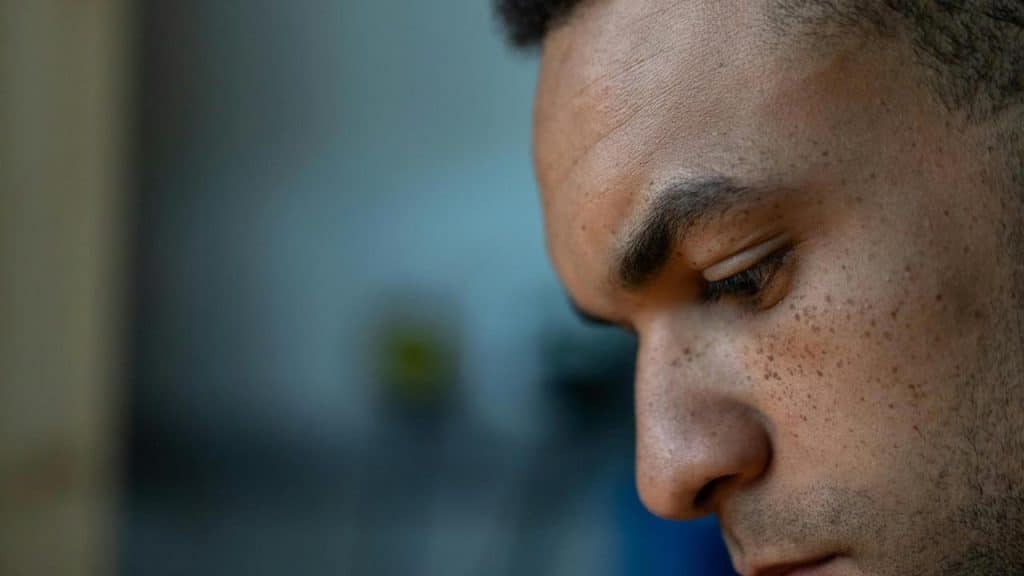 A close-up of a man looking down thoughtfully.