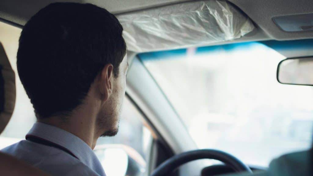 A man sitting in a car and looking out the window while driving.
