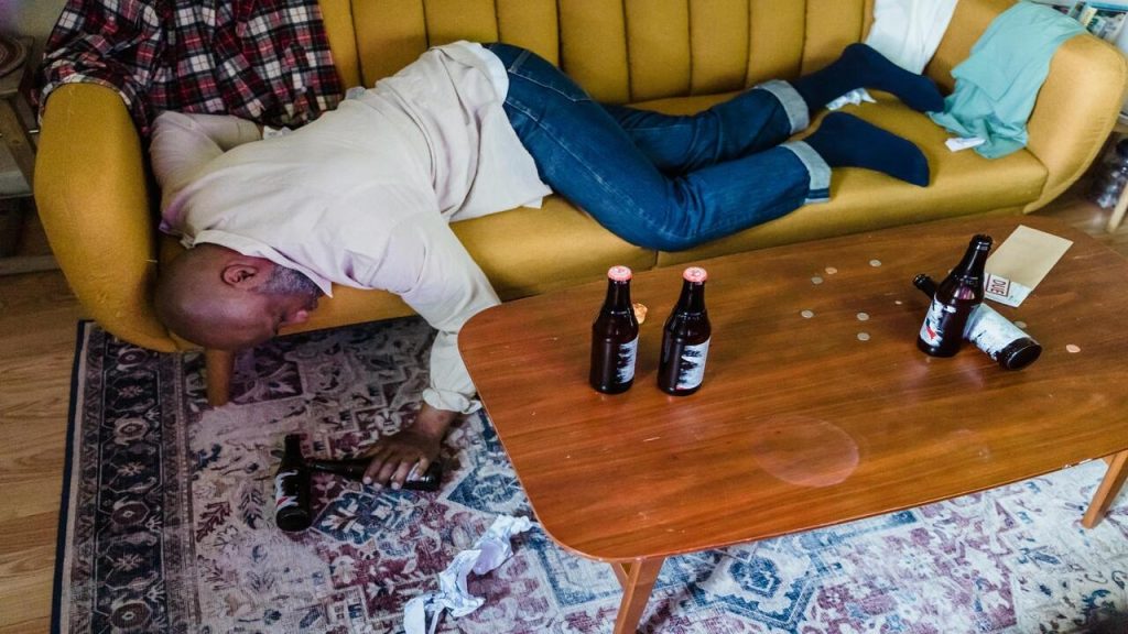 A man passed out on the couch due to drunkenness