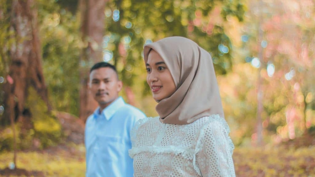 A man and woman standing in a forest.