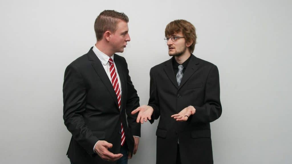 Two men in business suits having an animated conversation against a white background.