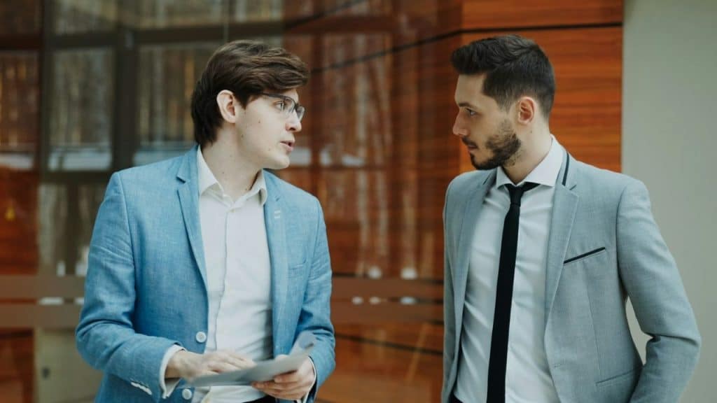 Two men in business attire having an intense conversation while standing indoors.
