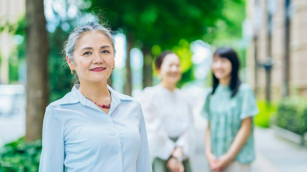 A woman standing with 2 women in the background.