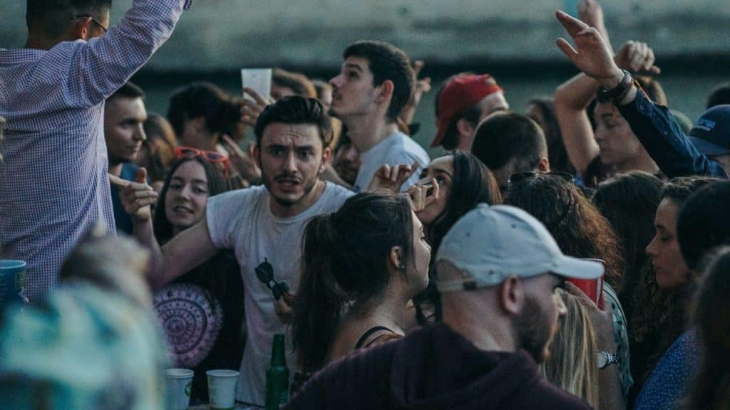 A dense crowd of young people socializing at an outdoor social event.